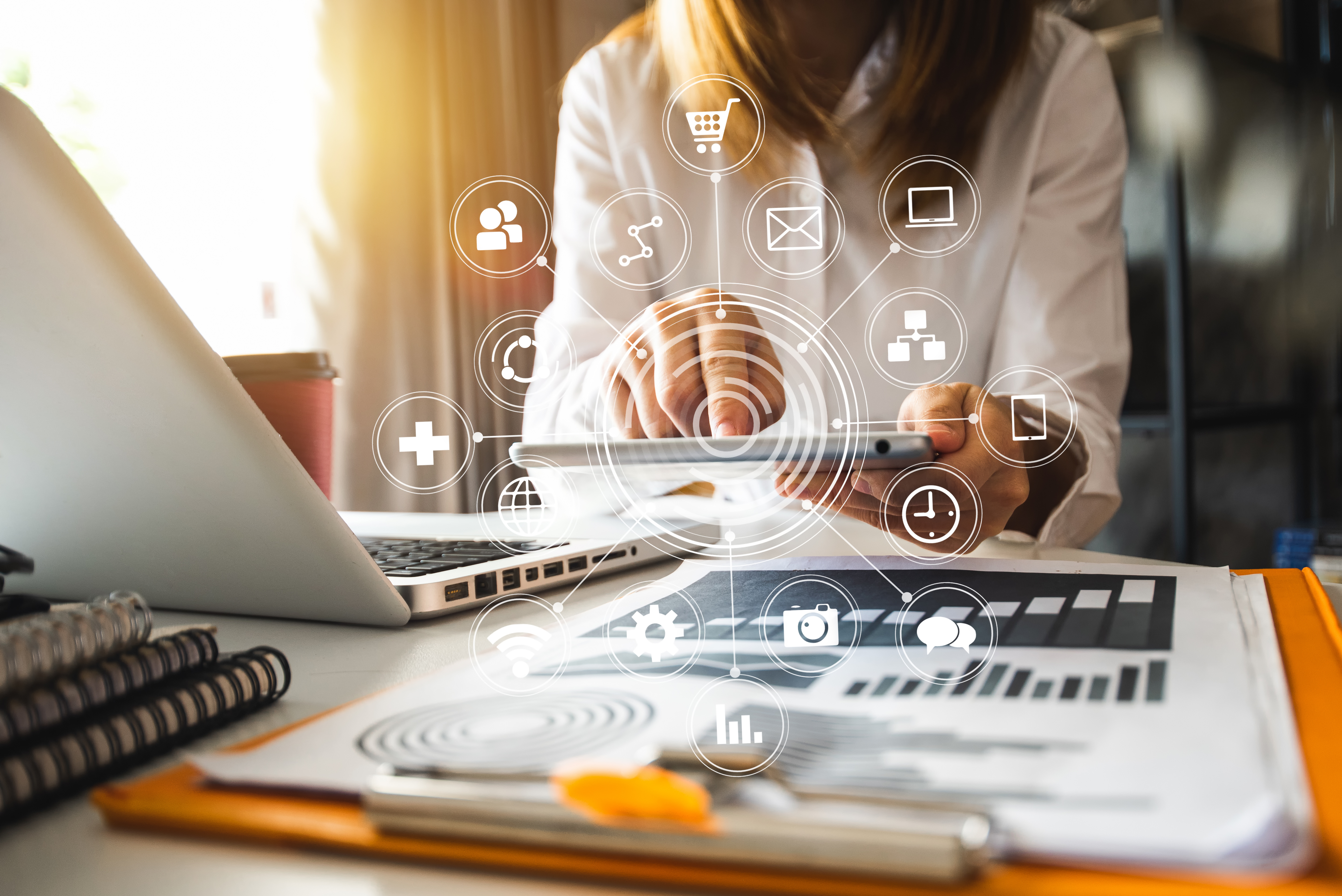 Icons representing digital business capabilities — commerce, communication, data, and connectivity — overlaid on a person using a phone near a laptop