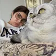 A woman wearing glasses and a cat relaxing on a sofa