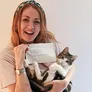 A woman holding a cat like a baby