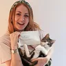A woman holding a cat like a baby