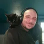 A black cat on the shoulders of a man wearing headphones