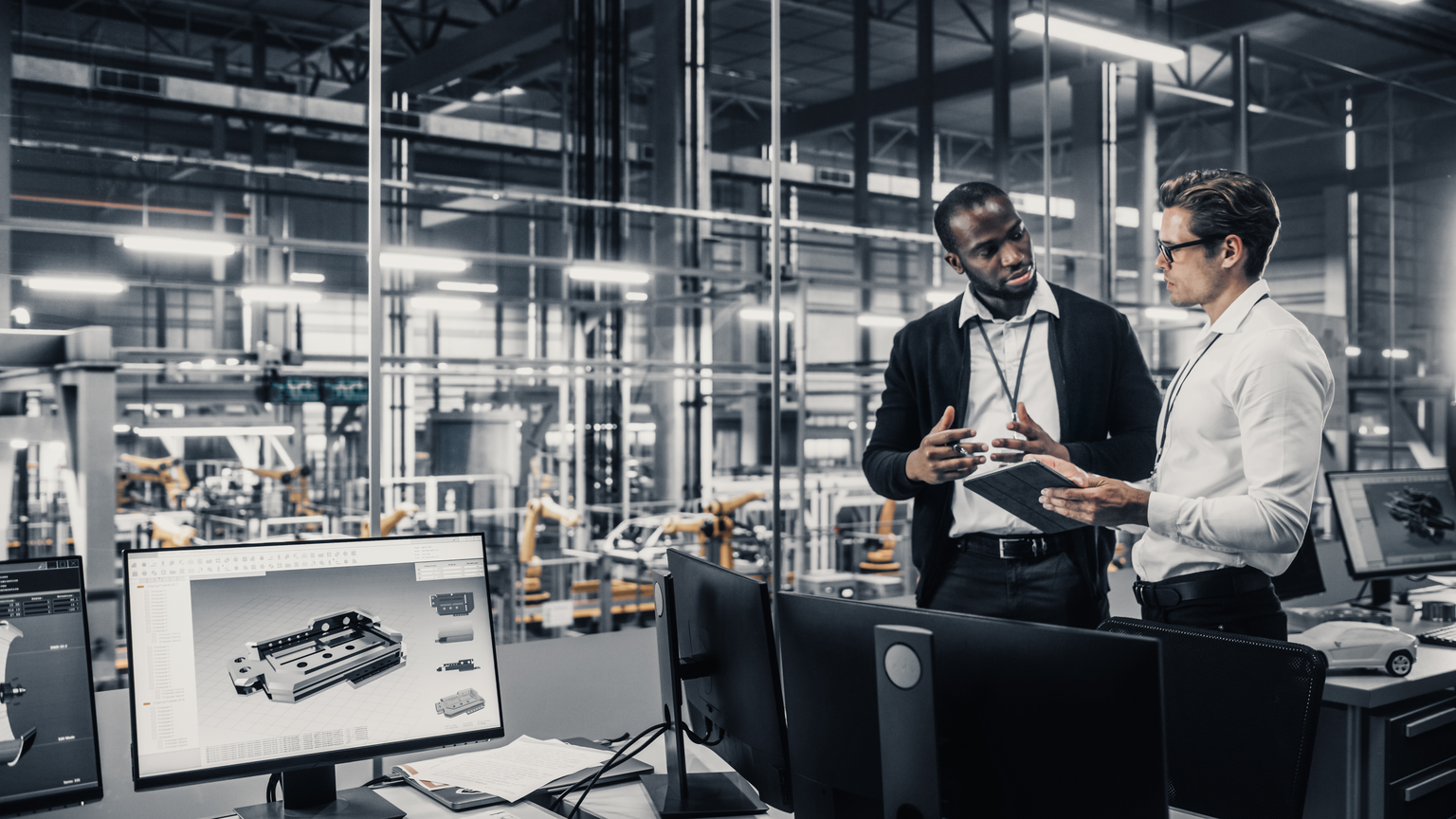 Zwei Männer unterhalten sich in einem modernen Büro in einer Produktionshalle