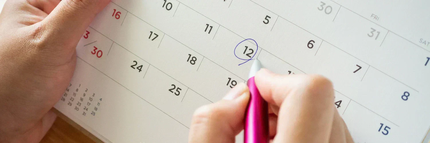 Ein Kalender in der Hand eines Person auf welchem die 12 des Monats eingekreist ist