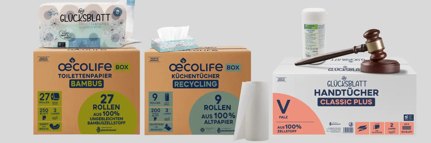 Präsentation umweltfreundlicher Papierprodukte, darunter Toilettenpapier aus Bambus, recycelte Küchenrollen und klassische Handtücher, daneben ein Richterhammer und eine Reinigungsmittelflasche.