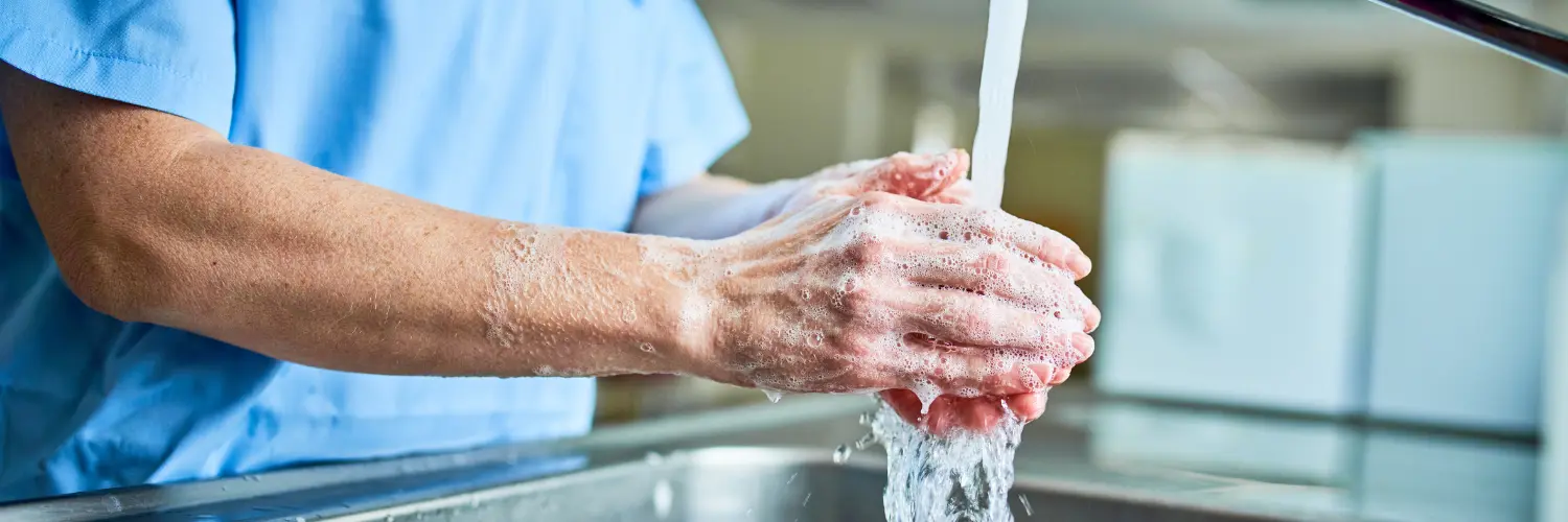Eine Person wäscht sich unter laufendem Wasser die Hände an einem Waschbecken