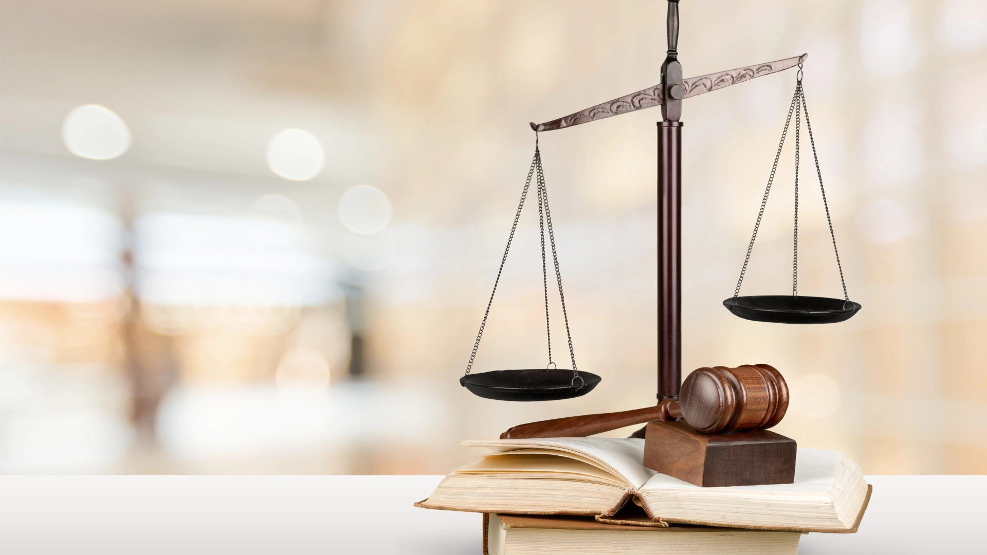 Eine Justitia-Waage und ein Richterhammer auf gestapelten Gesetzbüchern, die Recht und Ordnung vor einem verschwommenen Hintergrund symbolisieren.