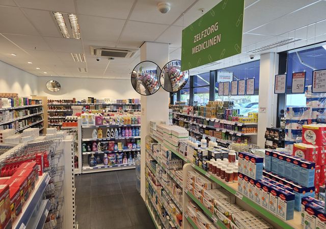 Interieur van een apotheek met planken vol met verschillende medicijnen en gezondheidsproducten. Er hangt een groen bord boven ons hoofd.