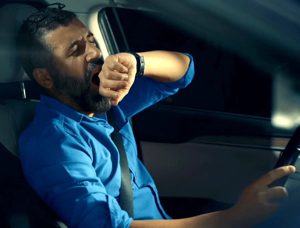 Man driving a car yawning
