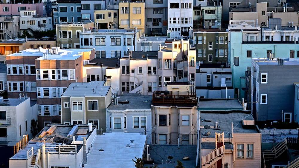 Aerial view of densely packed, colorful urban houses with flat roofs, showcasing architectural diversity and closely-knit residential setup.