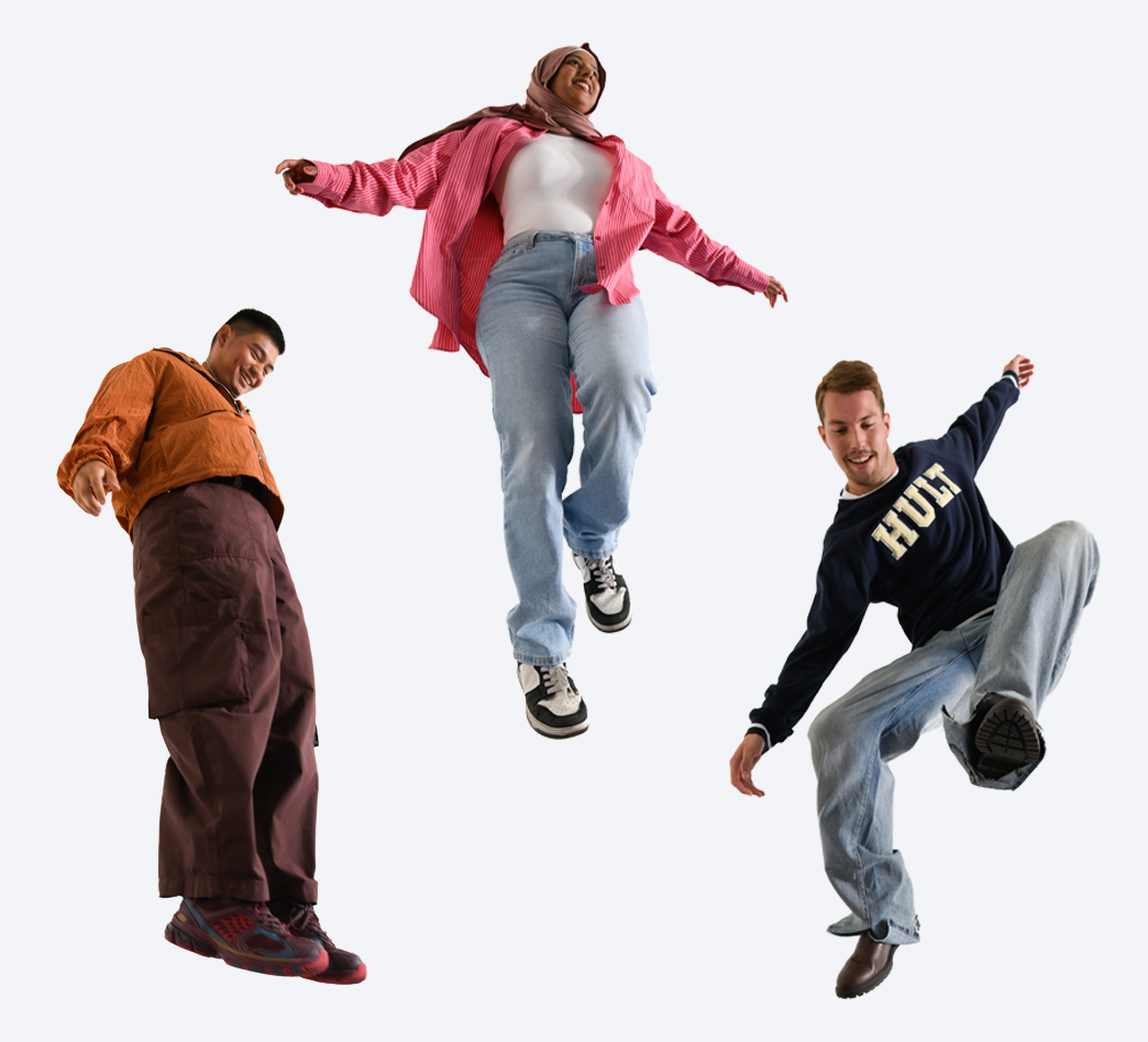 Three people in casual clothing, mid-jump against a white background, smiling and energetically posed.