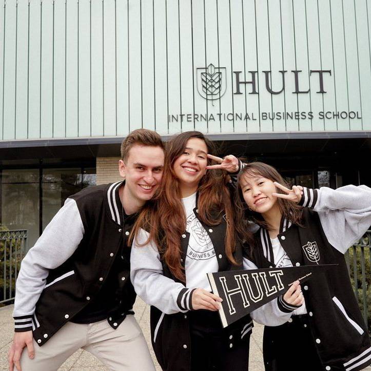 Three students pose happily in front of Hult International Business School.