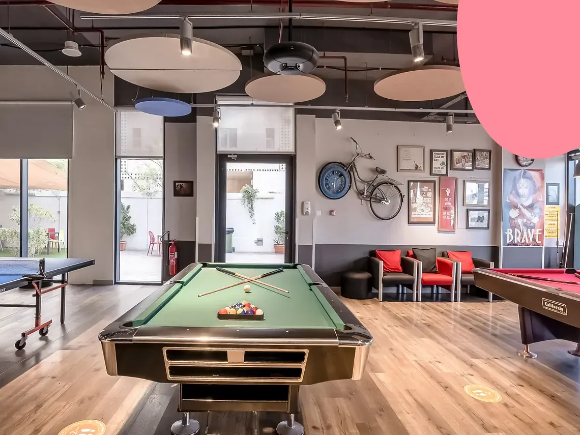 Modern game room with pool, ping pong tables, wall art, and seating area. Decor includes a bicycle and framed pictures.