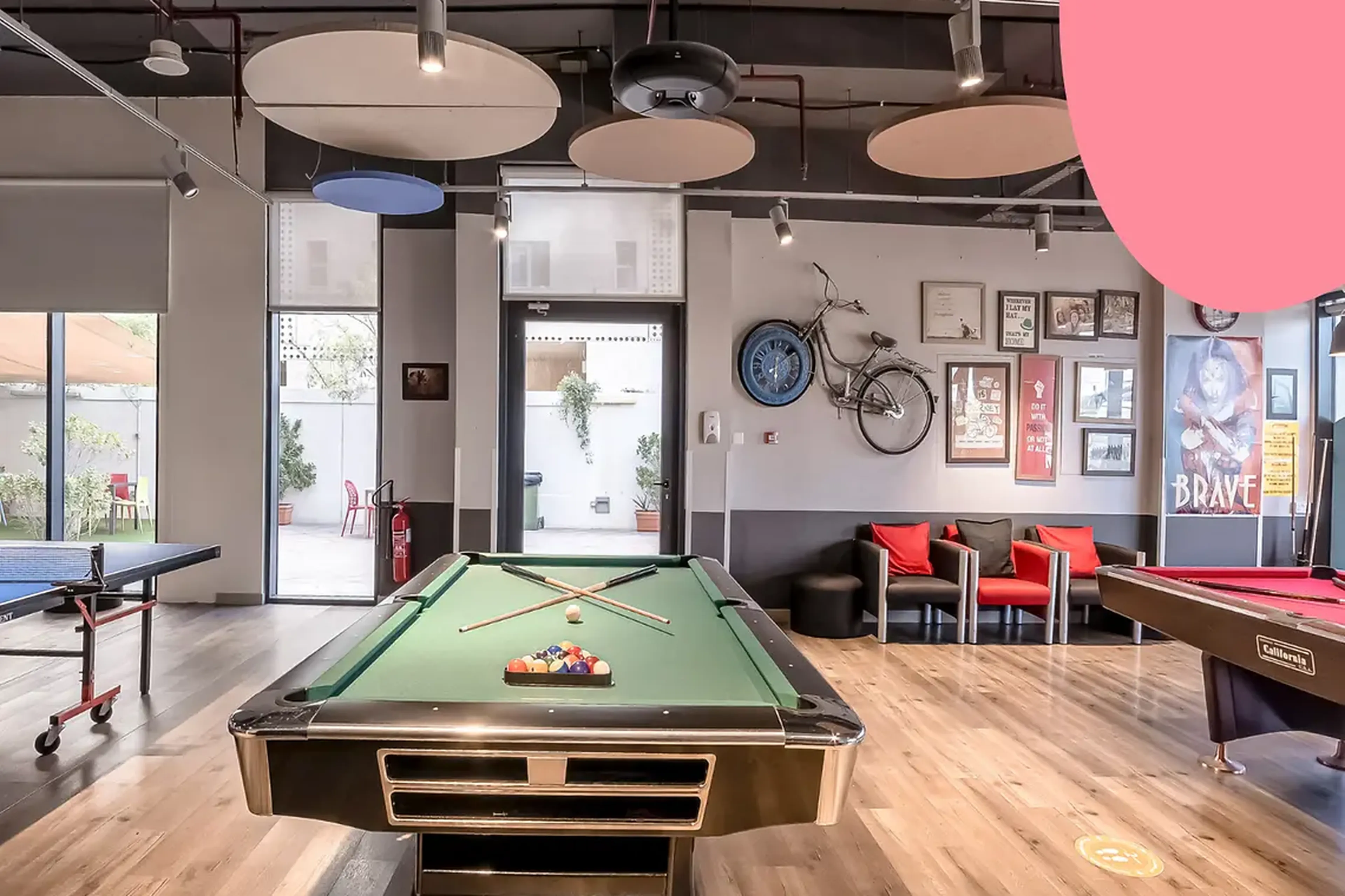 Modern game room with pool, ping pong tables, wall art, and seating area. Decor includes a bicycle and framed pictures.