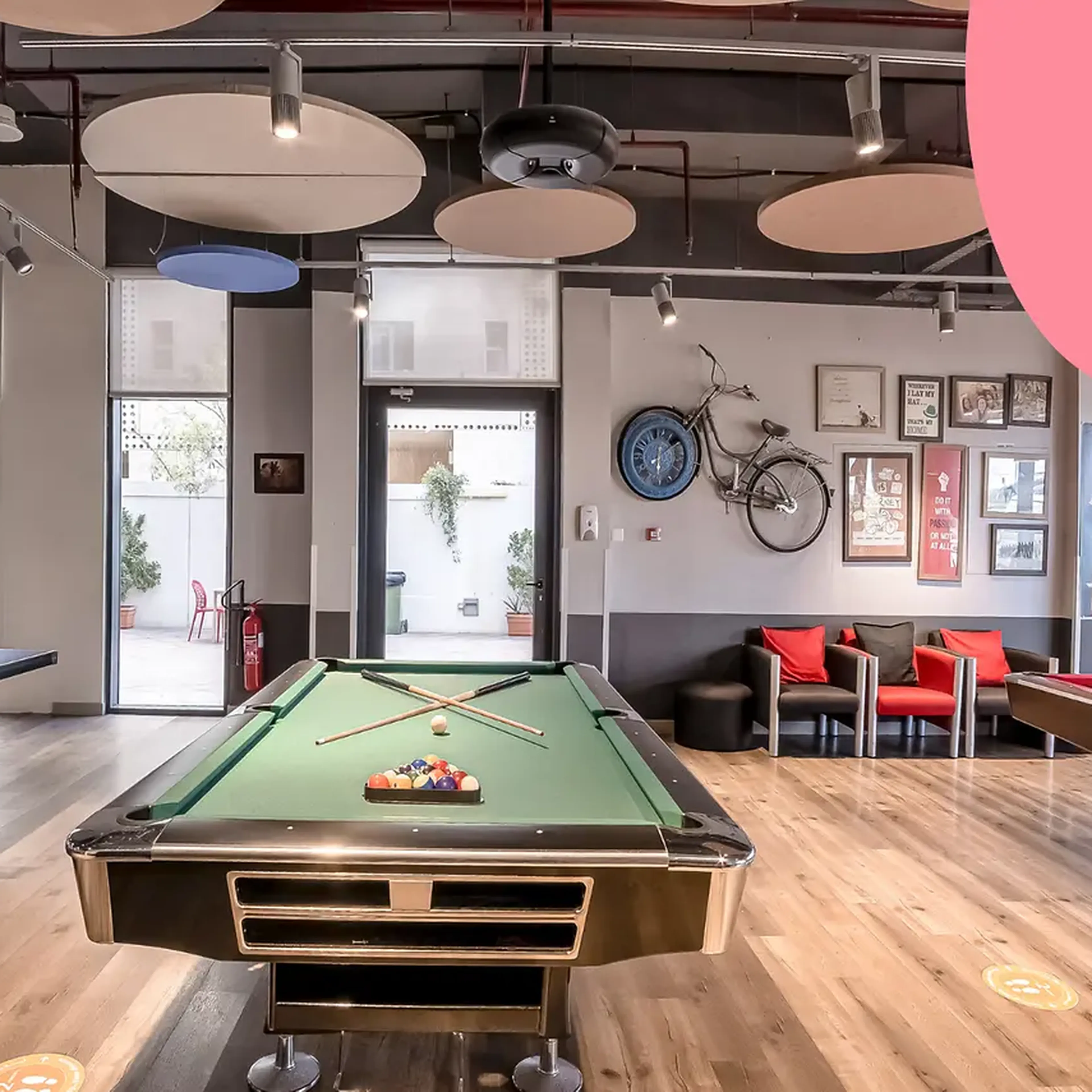 Modern game room with pool, ping pong tables, wall art, and seating area. Decor includes a bicycle and framed pictures.