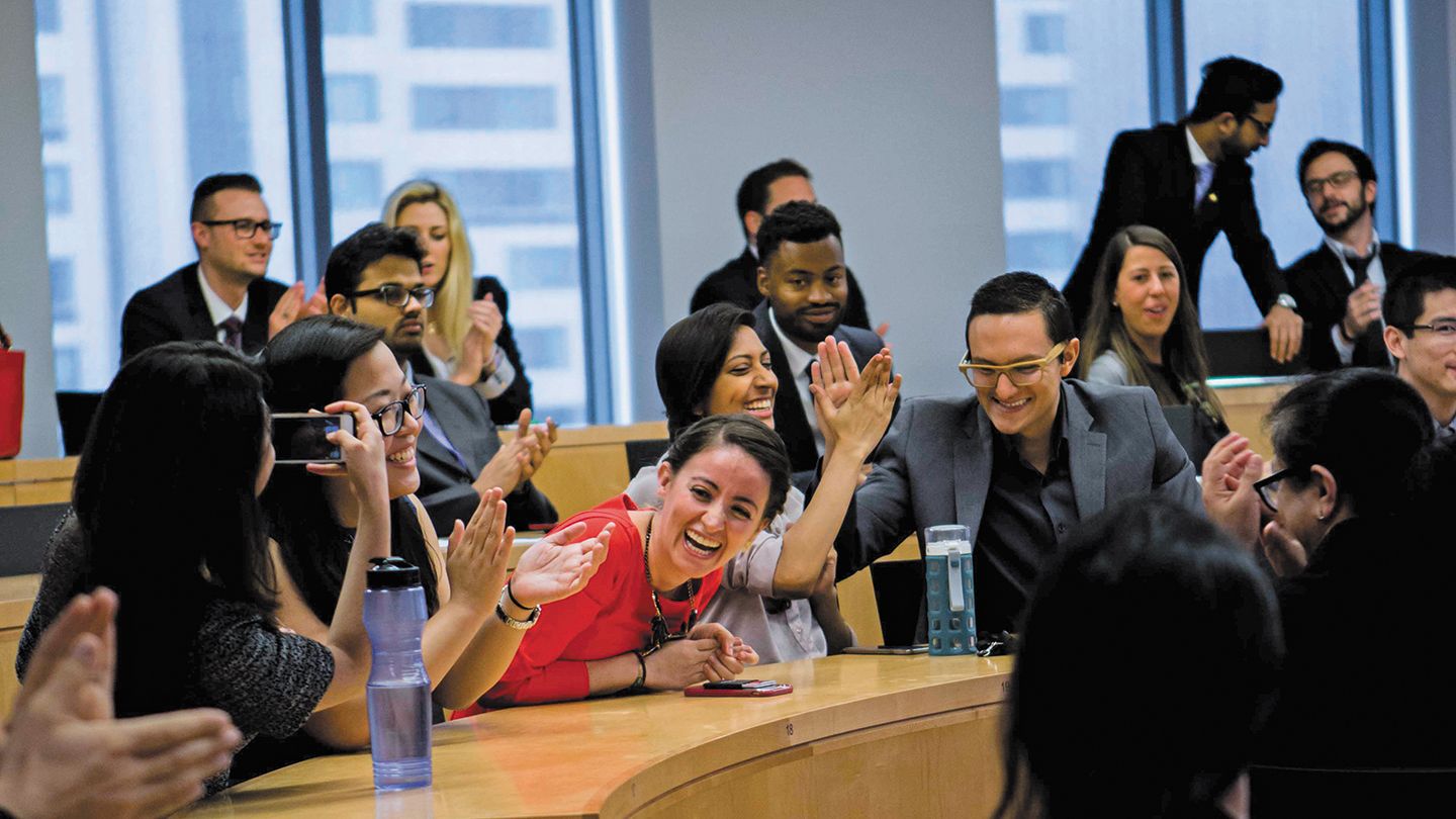 Diverse group of students in a conference room, smiling and high-fiving.