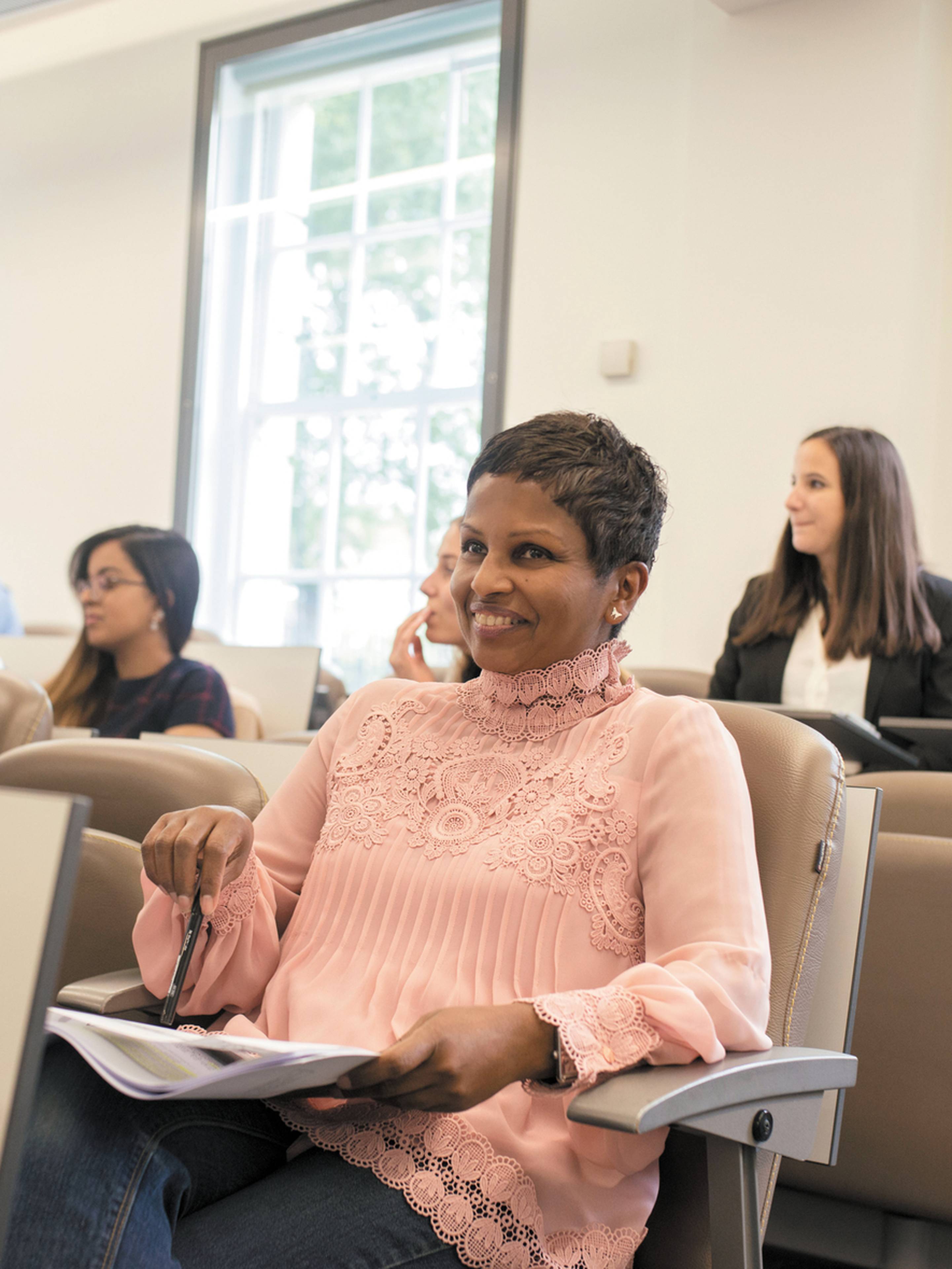 People sitting in a classroom, listening and smiling during a lecture.