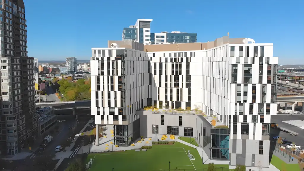 Aerial view of a modern, white building with a geometric facade and urban surroundings.