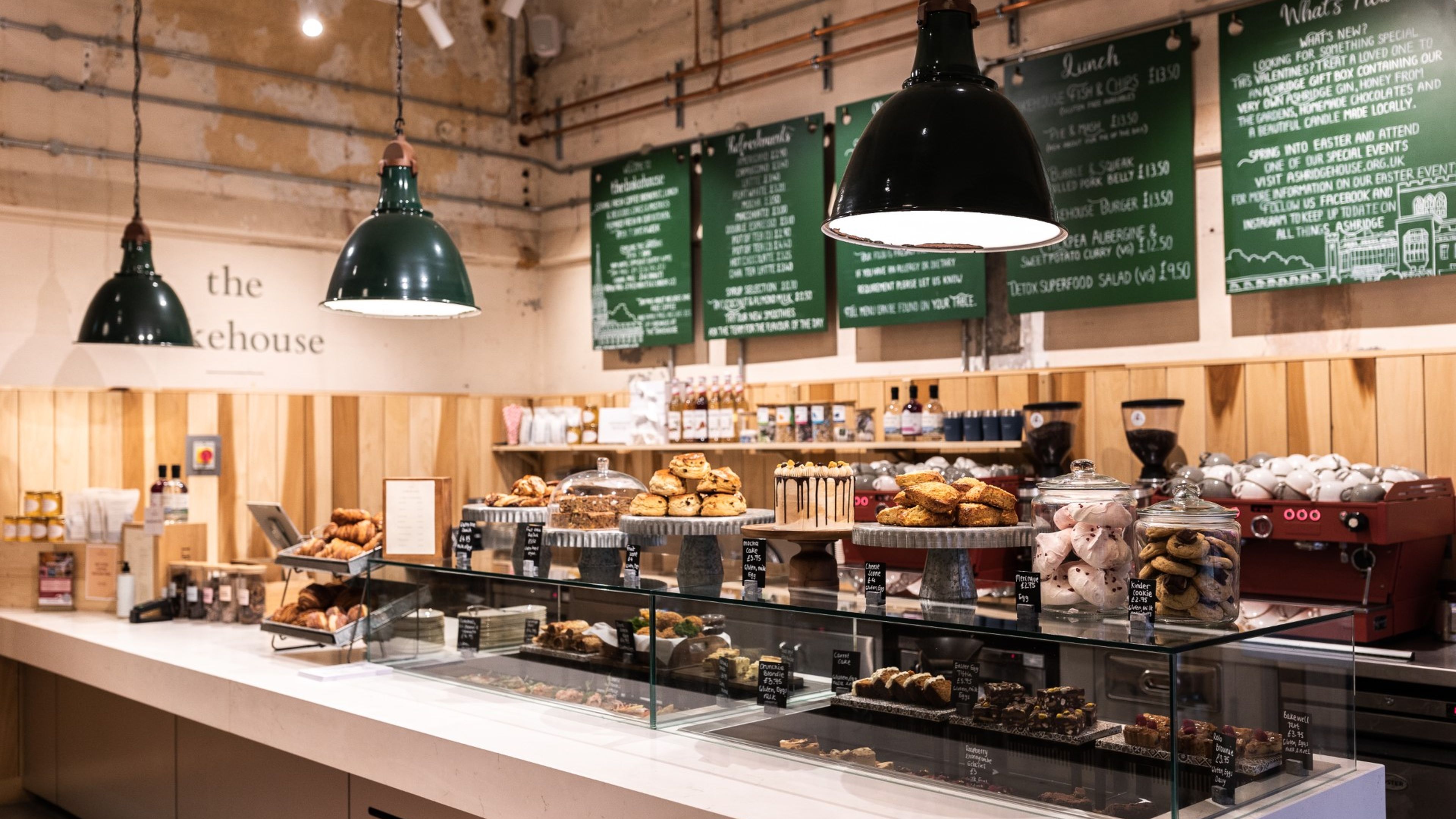 Cozy café interior with a pastry display, chalkboard menus, and industrial-style lights.