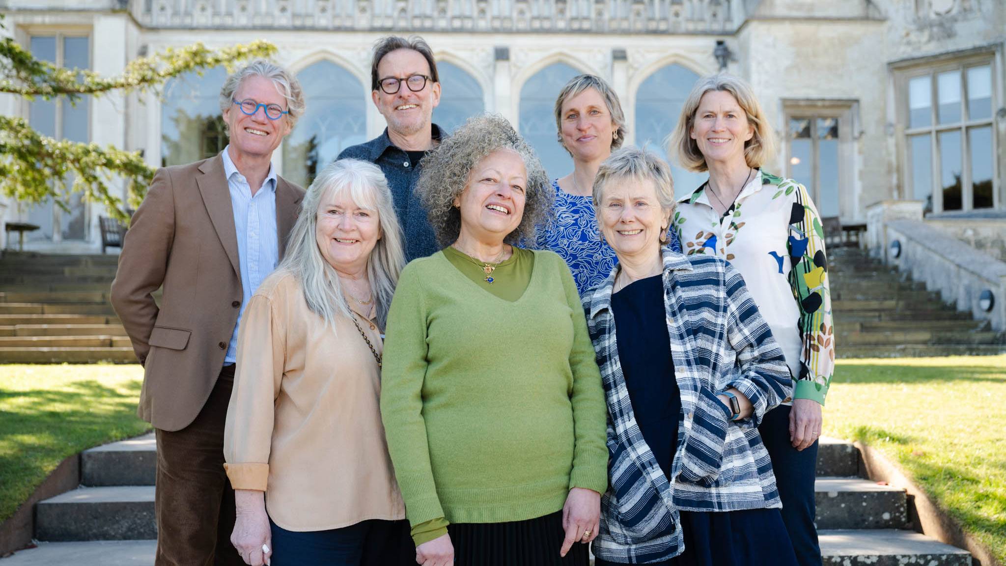 A group of eight people smiling in front of a historic building.