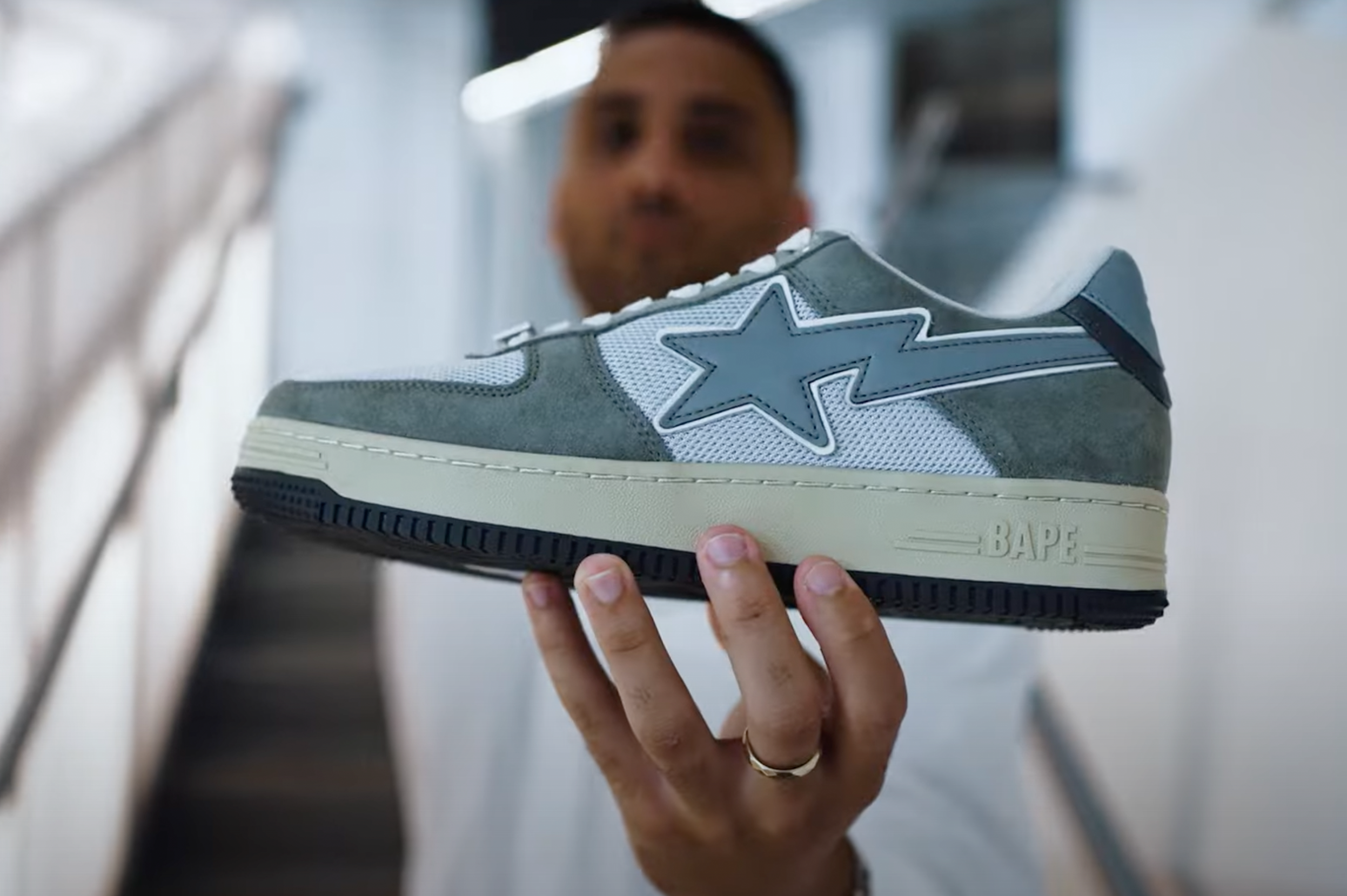 Man holding a grey and white BAPE sneaker with a star logo.