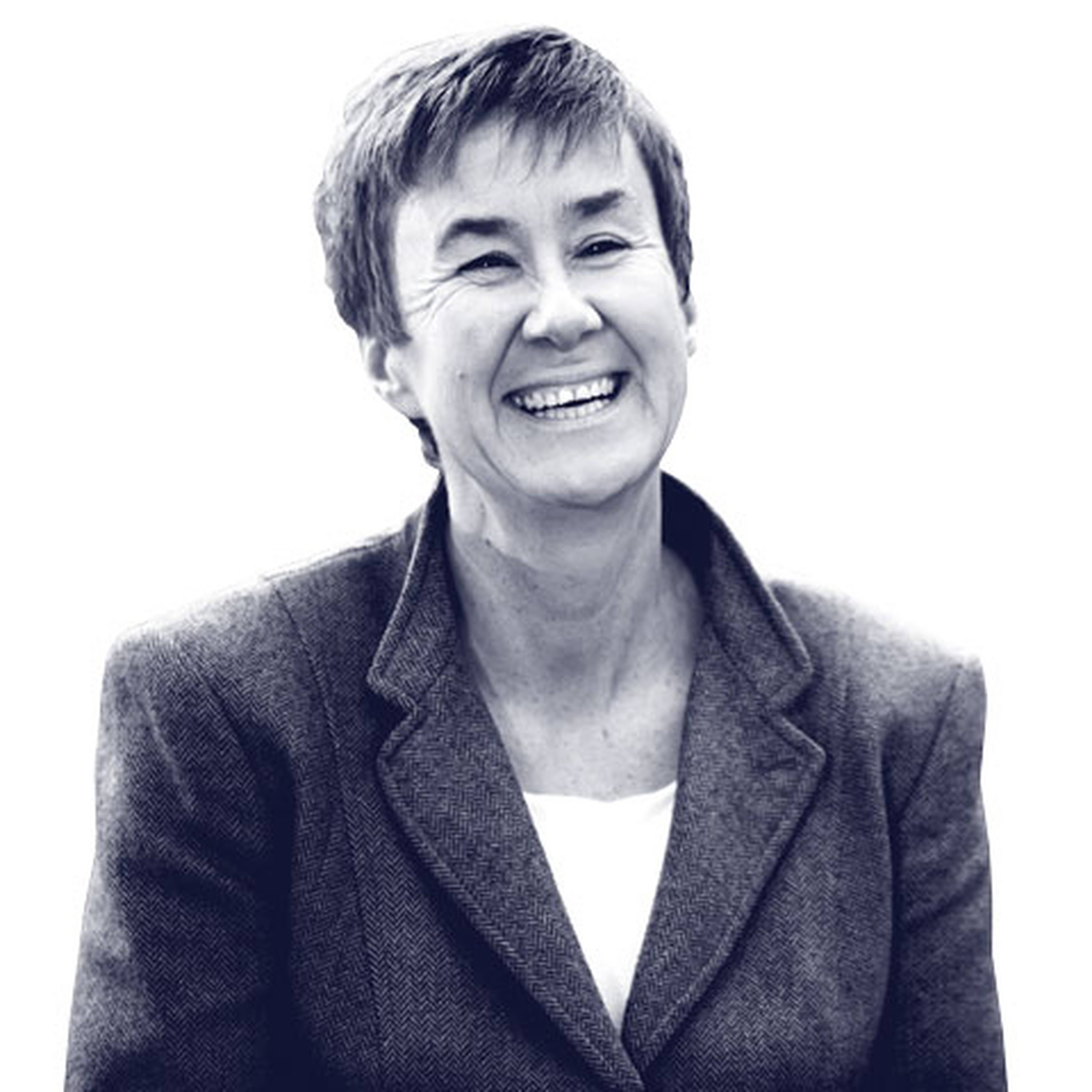 Smiling person in a suit looking slightly to the side against a white background.