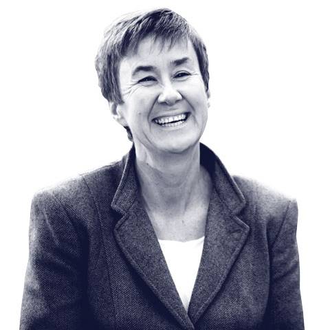 Smiling person in a suit looking slightly to the side against a white background.