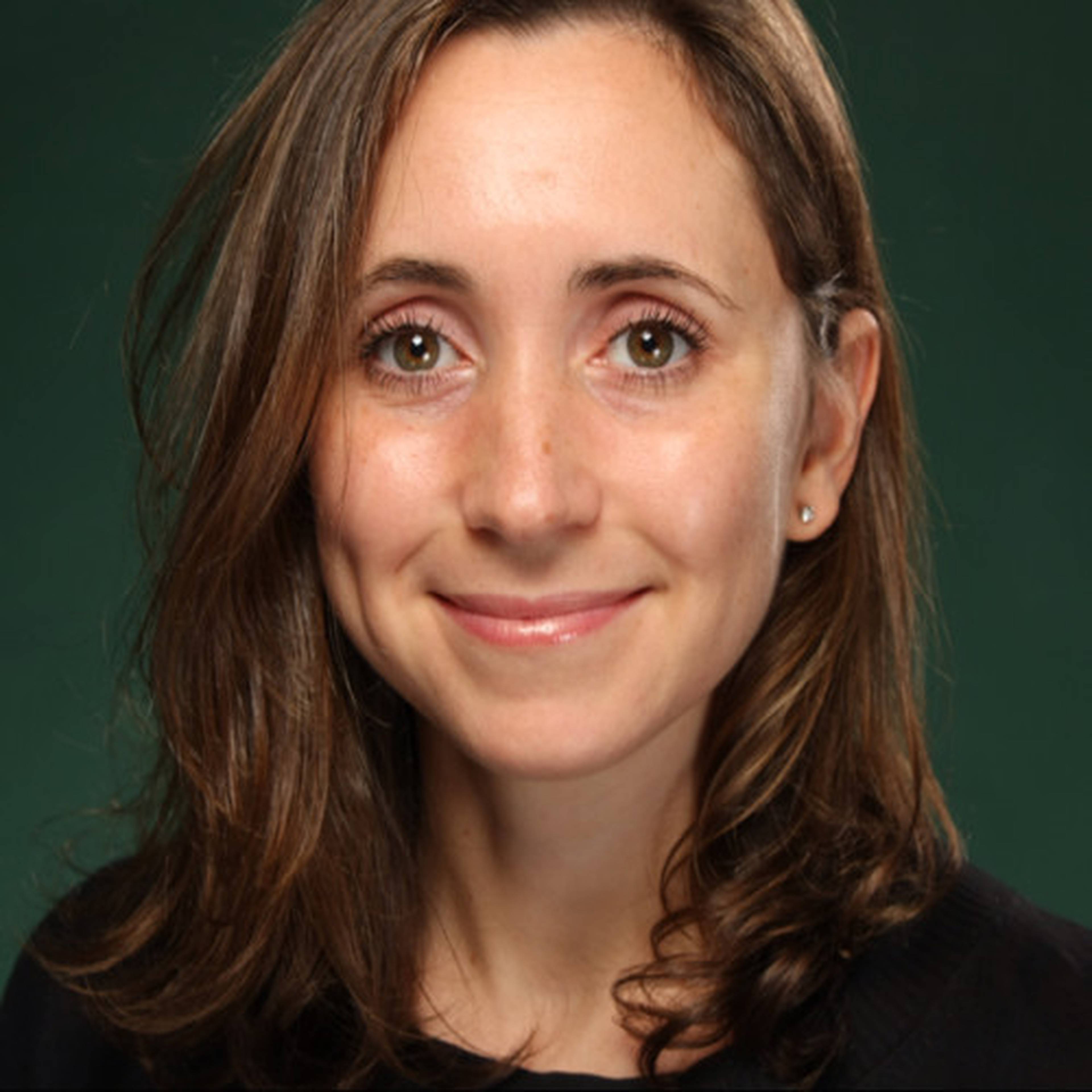 Smiling woman with shoulder-length brown hair and green eyes, wearing a black top.