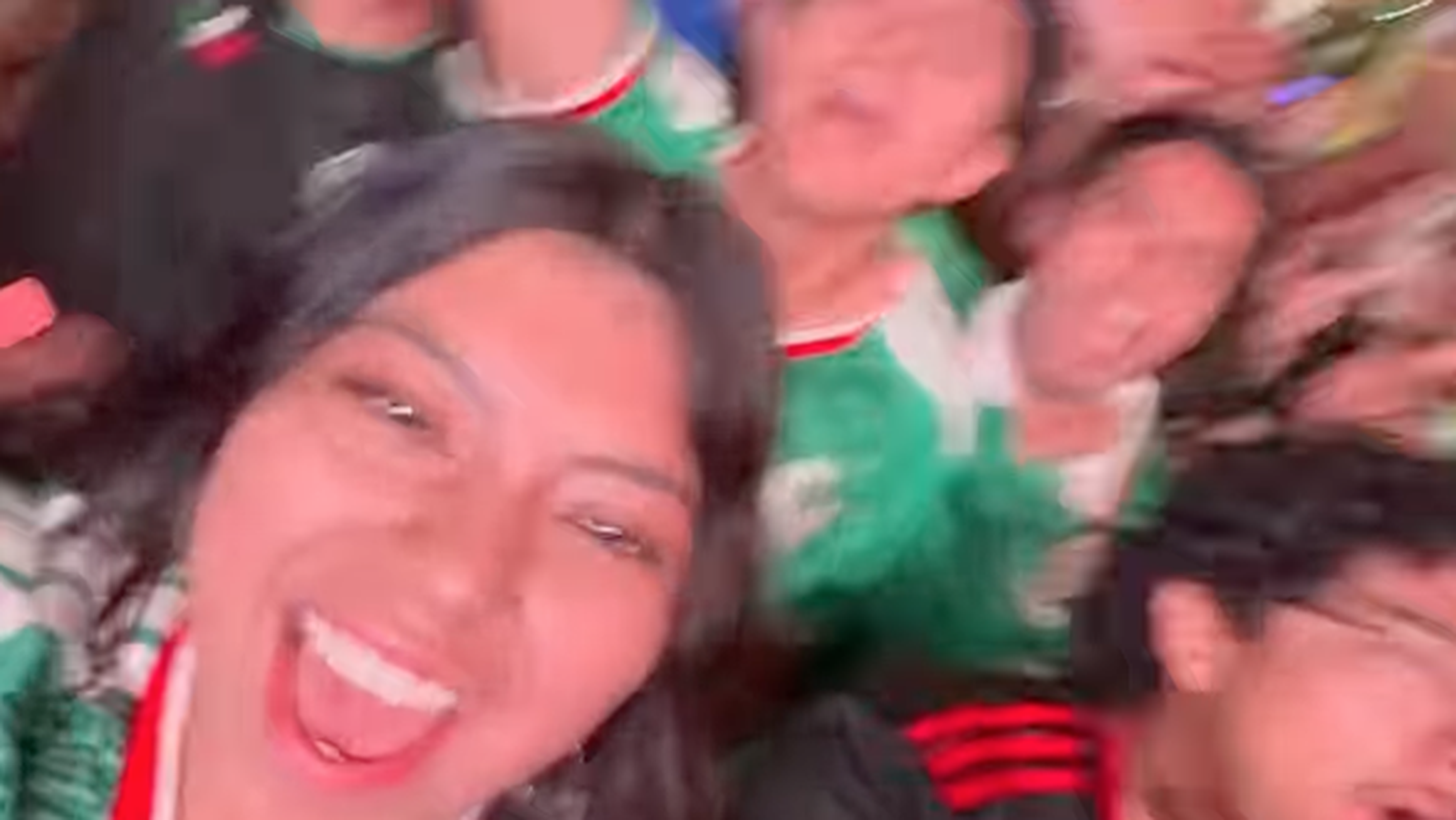 Crowd of people smiling and cheering in green sports jerseys.
