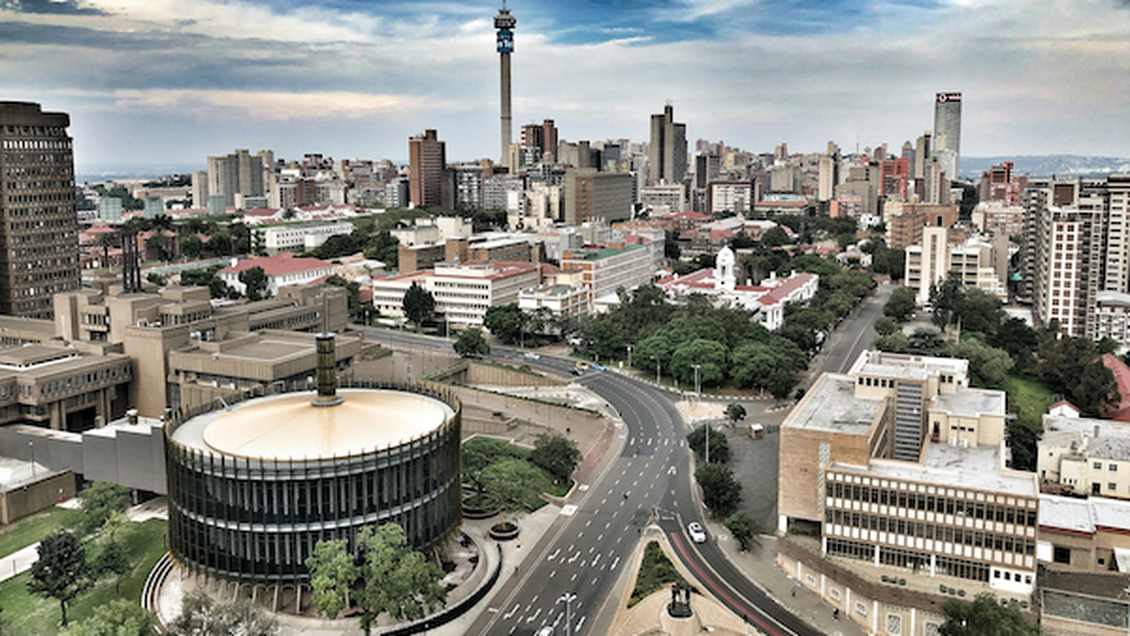 Aerial view of a busy urban skyline with distinctive towers and surrounding greenery.