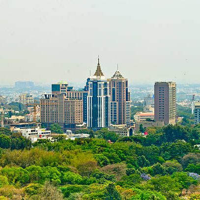 Tall buildings rise above lush greenery in a sprawling urban landscape.