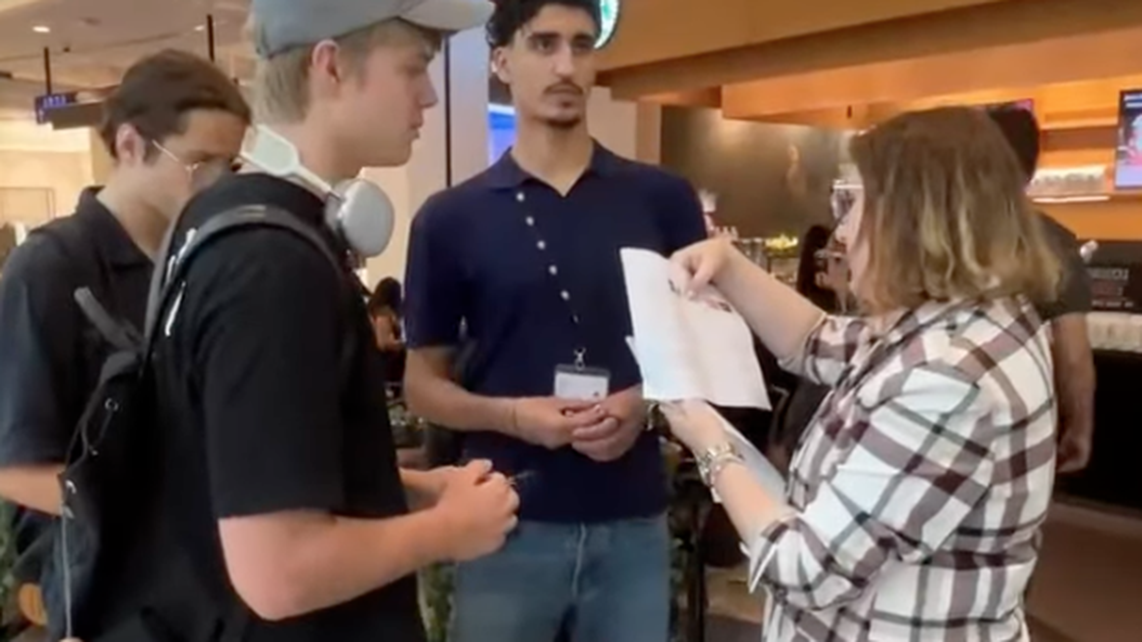 A woman shows a paper to a group of people in front of a Starbucks.