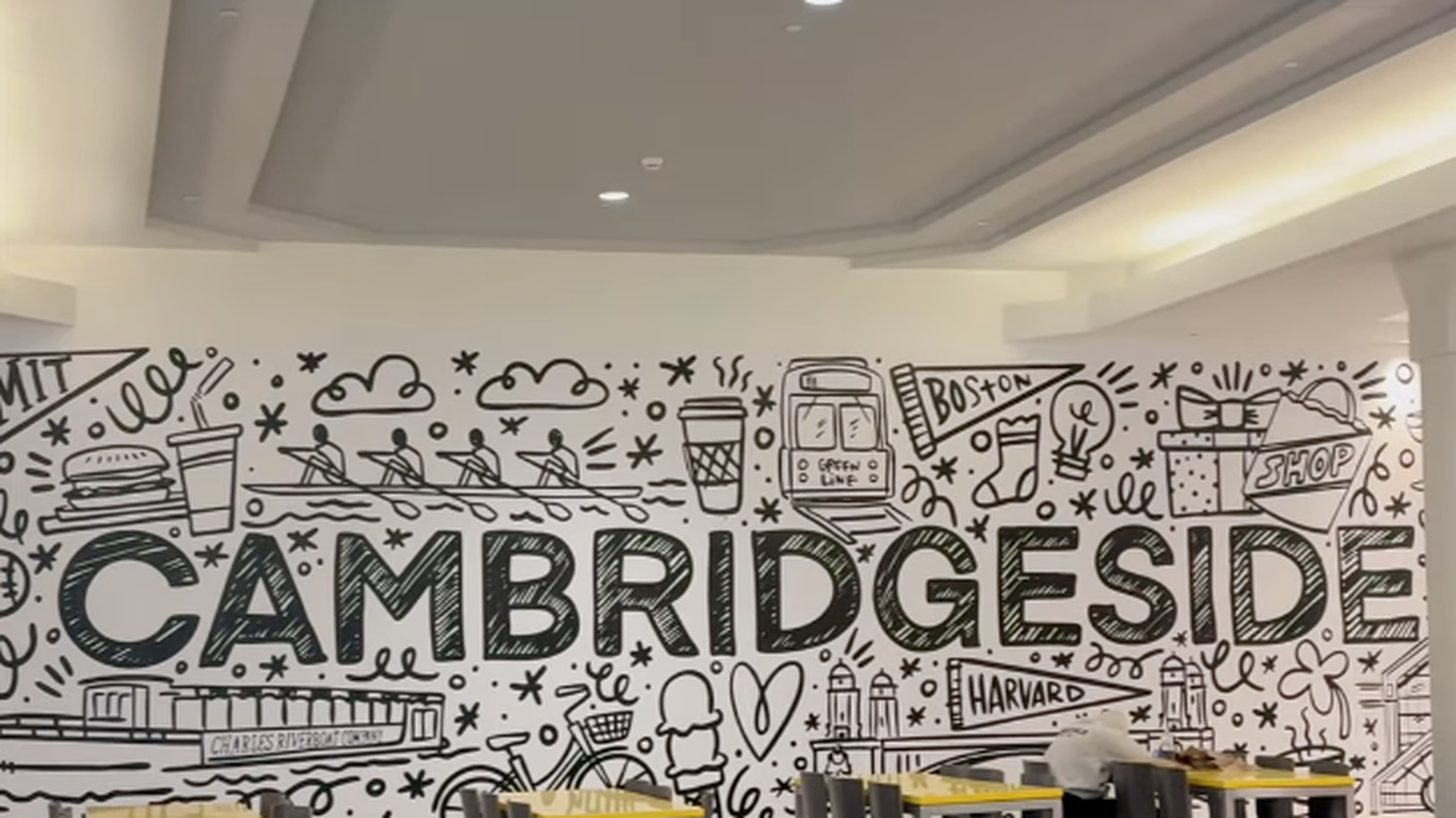 Mural with "CAMBRIDGESIDE" and illustrated icons, chairs and tables lined below.