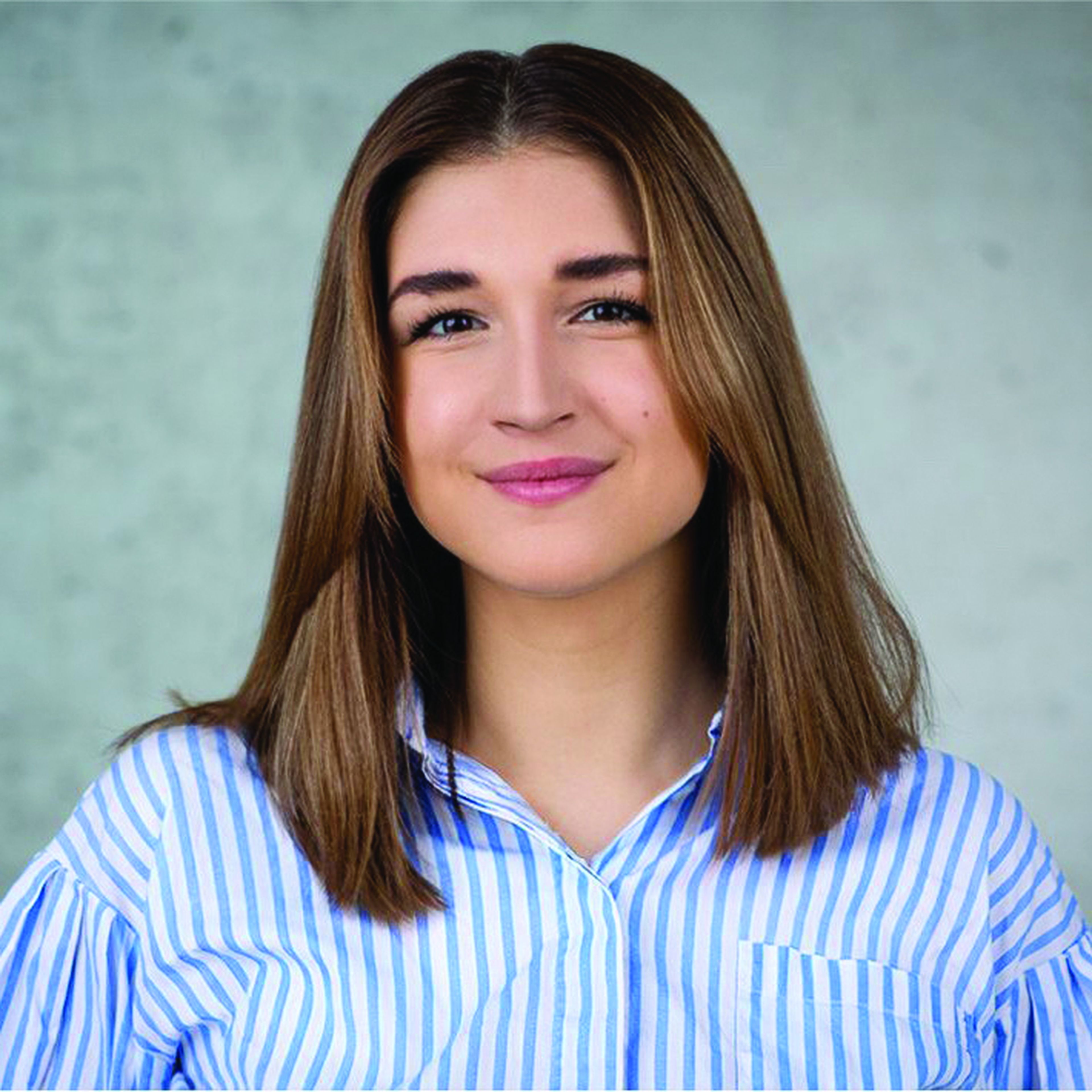 Person with shoulder-length hair and striped shirt smiling at camera.