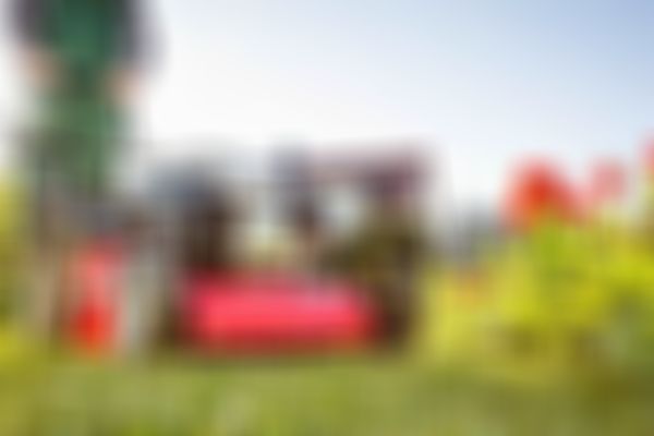 Person mit Rasenmäher in Garten