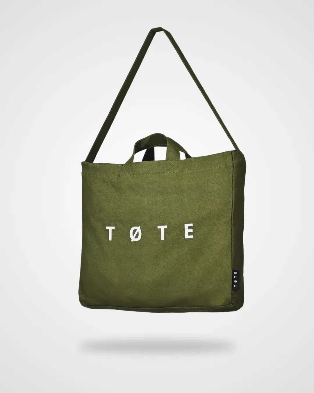Olive green canvas tote bag with a shoulder strap and the word "TØTE" printed in white on the front.