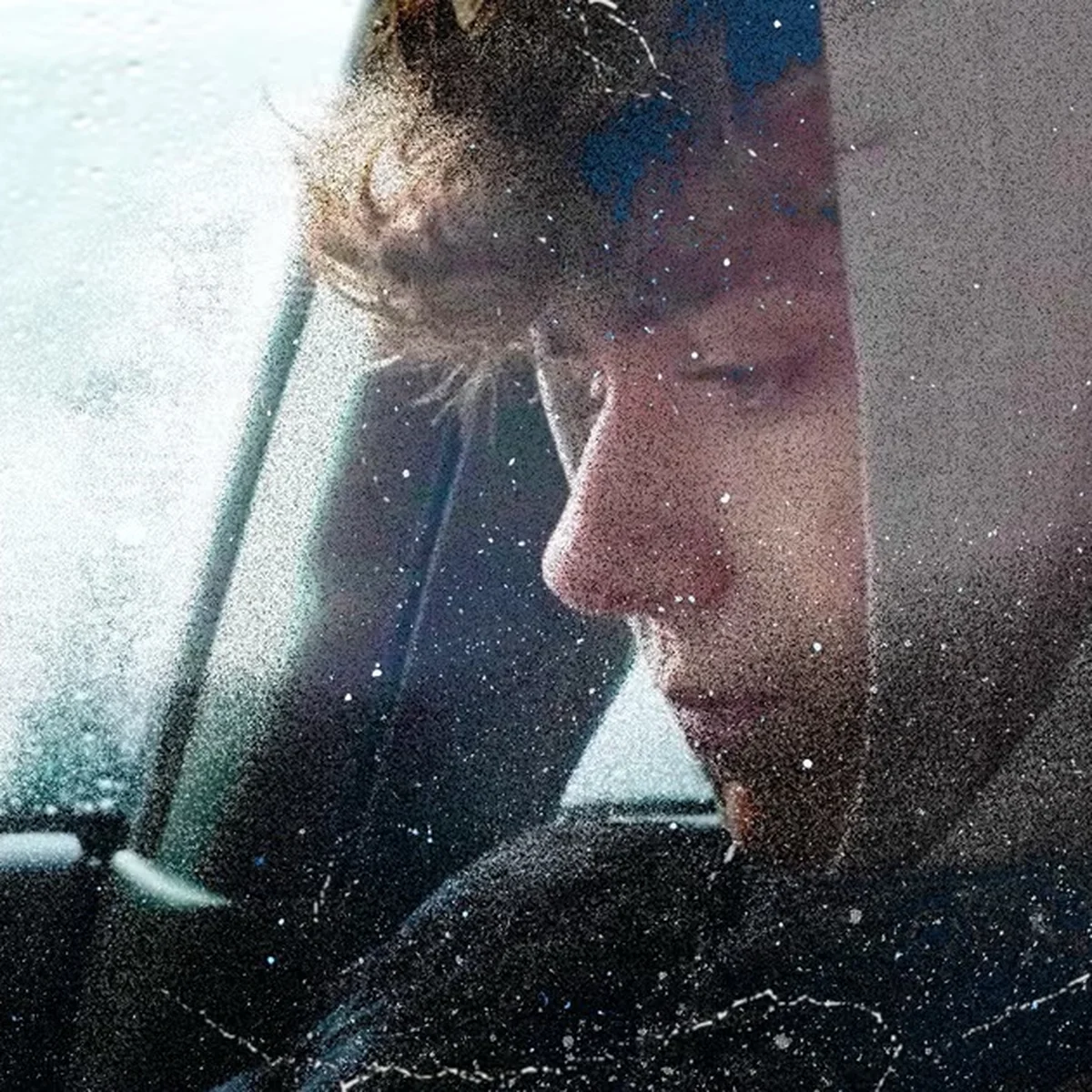 Young person with curly hair in a hoodie, sitting in a car, looking down pensively. Rainy window and vintage texture effect visible.