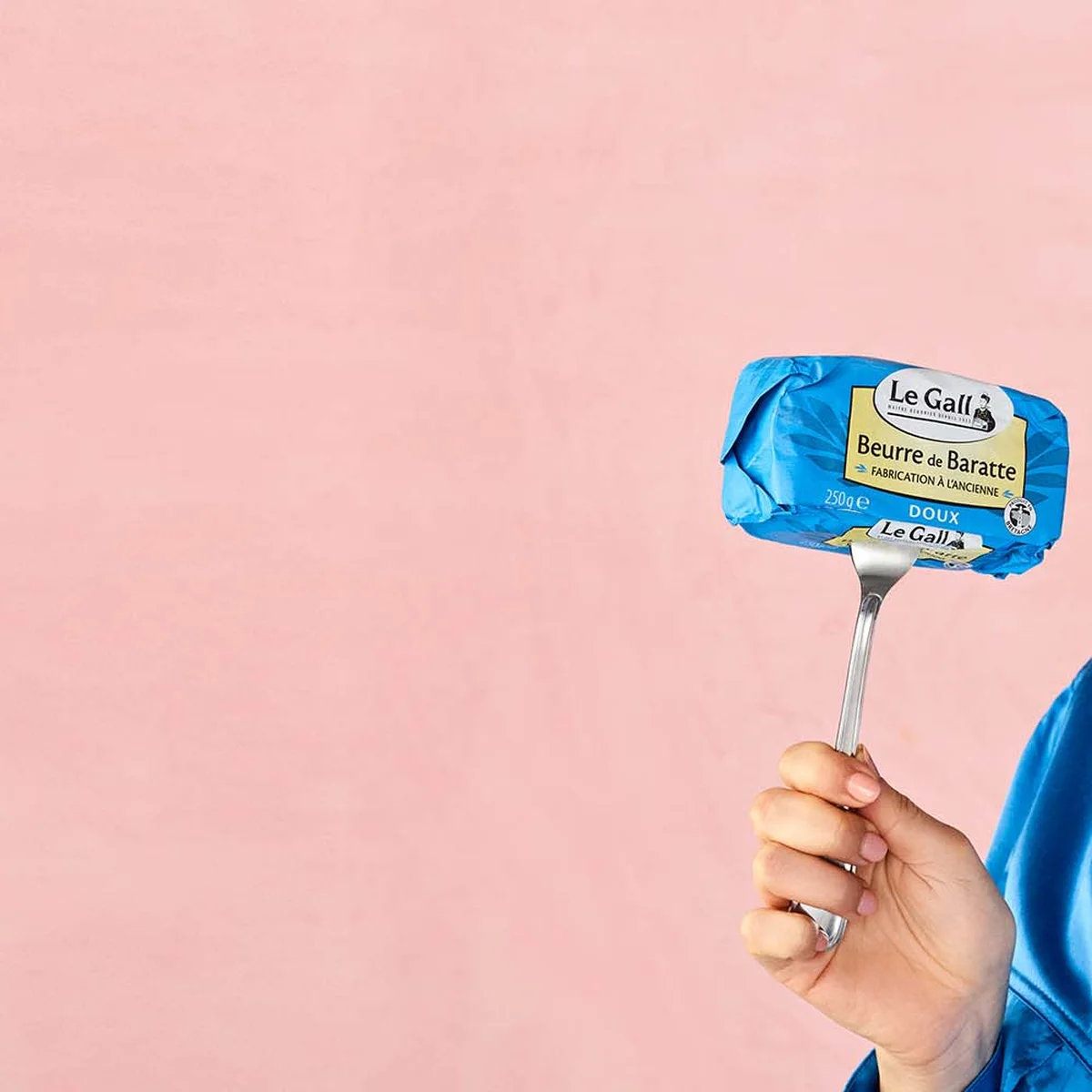 vrouw met een vork in de hand, waarop een stick boter zit en ze knipoogt