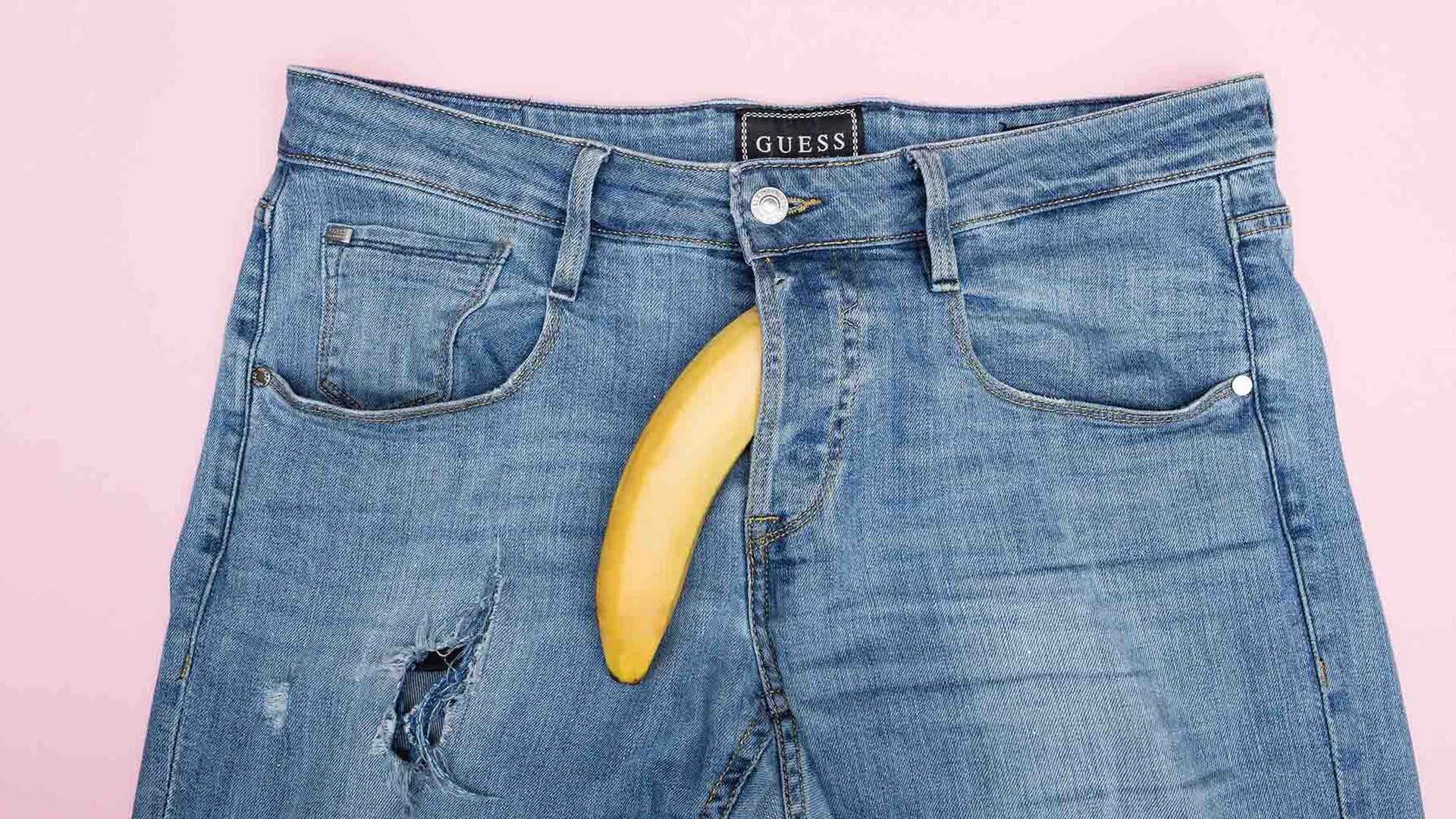 blauwe broek op een roze achtergrond met een banaan uit de gulp