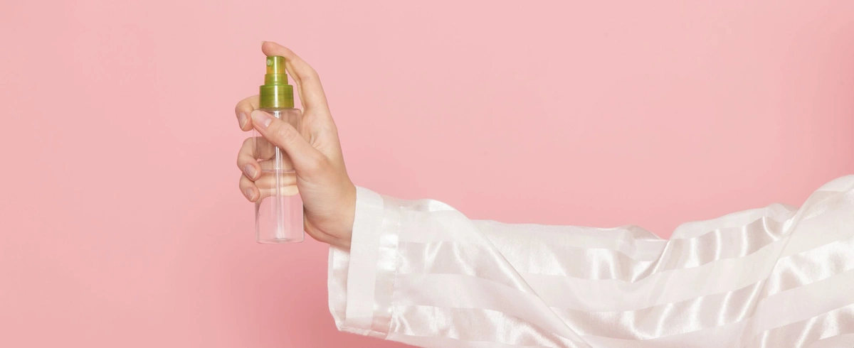 young-female-pajamas-sleep-mask-holding-make-up-spray-pink