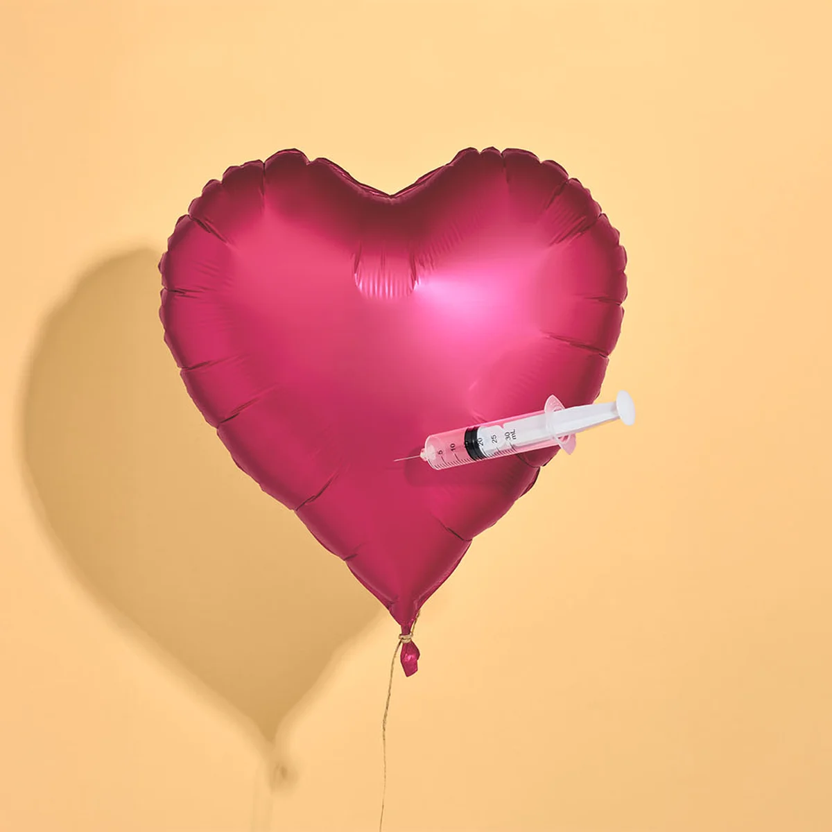 Roze balon geprikt door een spuit