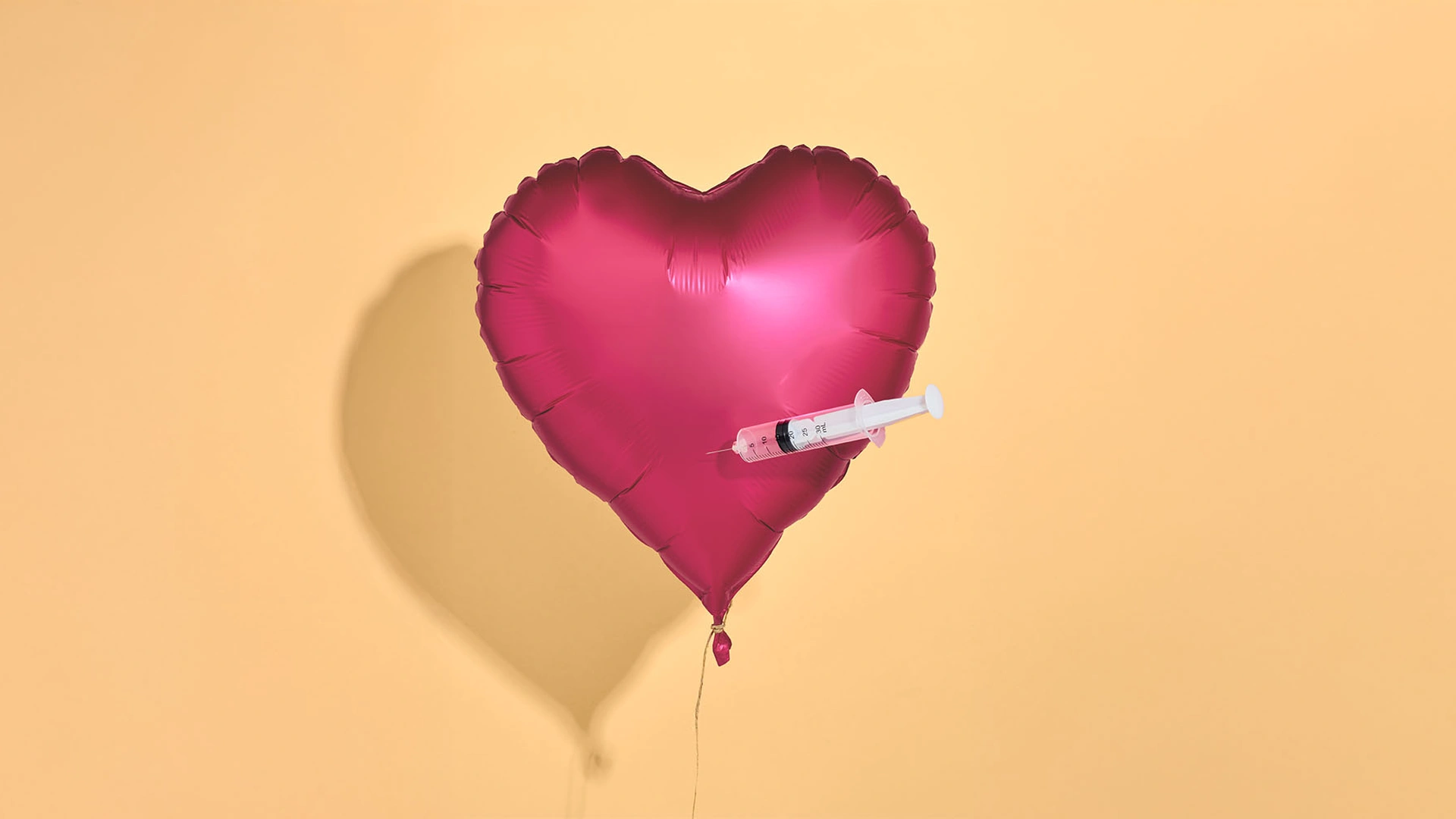 Roze balon geprikt door een spuit