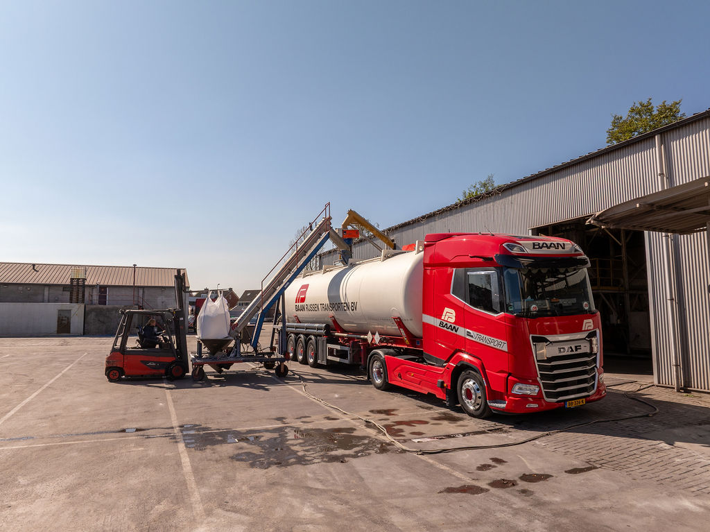 Rode BAAN tankwagen wordt geladen met bulkmateriaal bij silo-installatie van Baan Rijssen Transporten in Rijssen