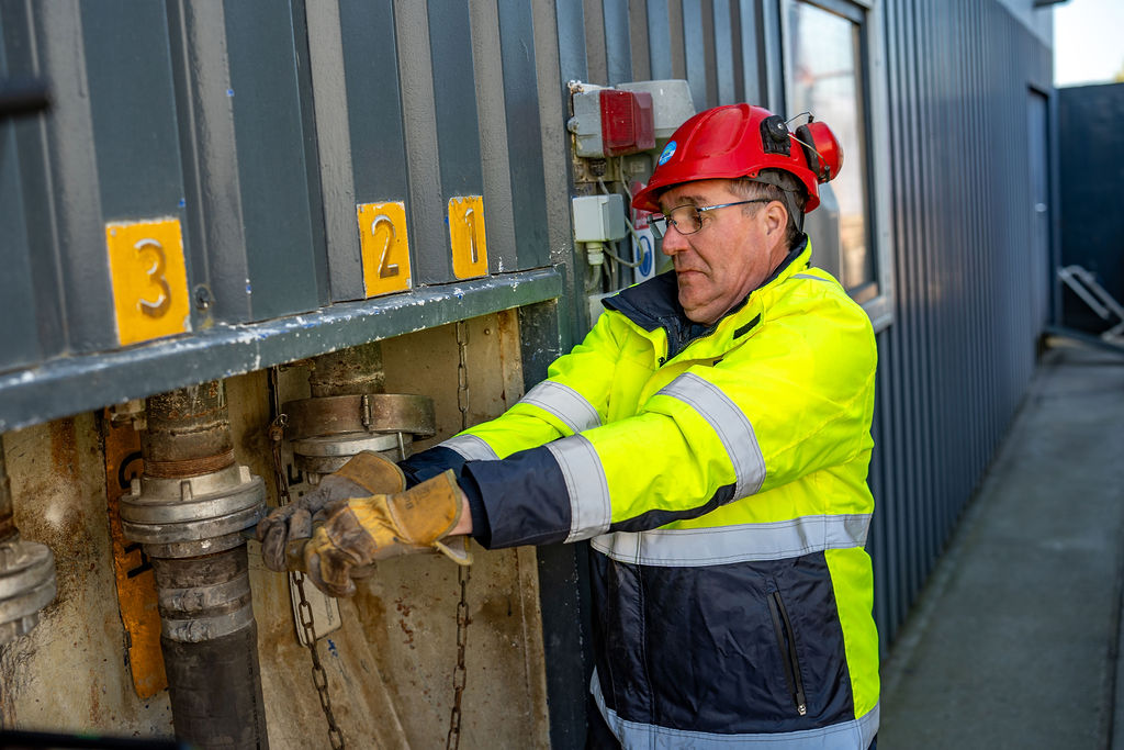 BAAN safety operator in helmet and hi-vis connecting numbered loading ports for ADR fly ash and waste material transport