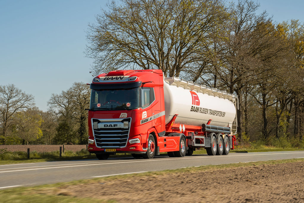 Red BAAN tipping bulk tanker on the road delivering powder cargo across Europe