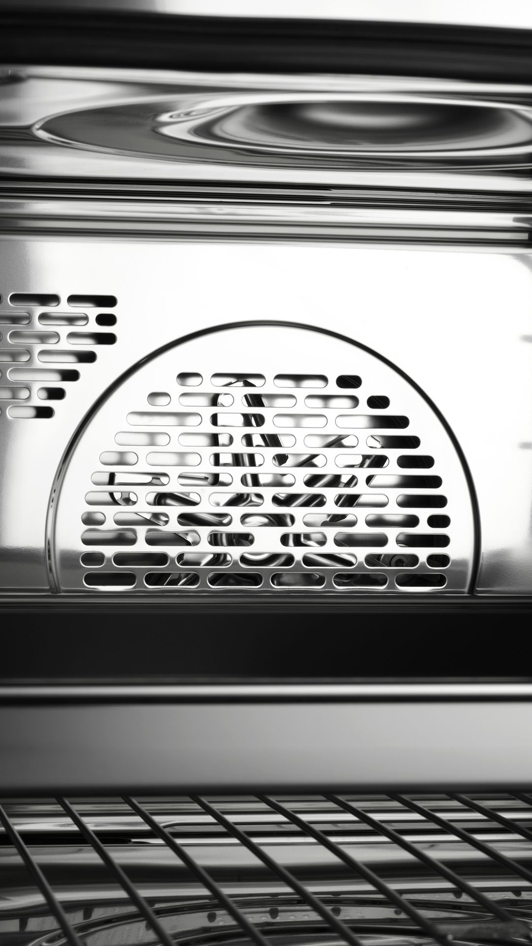 Close-up of the interior of an oven with stainless steel and fan cover.