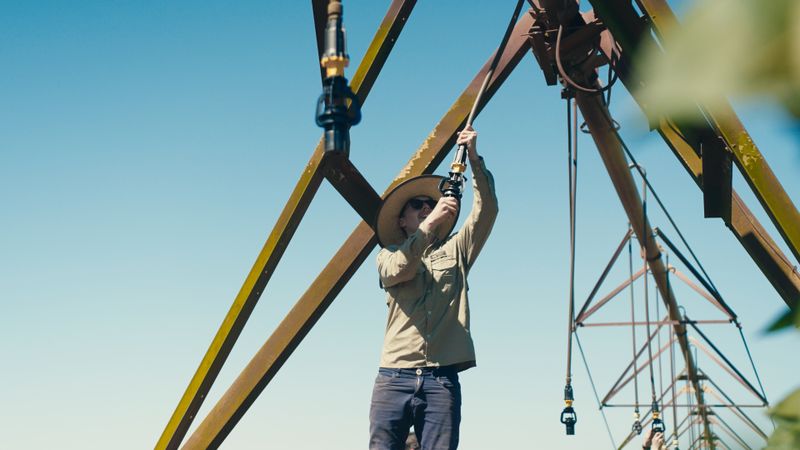 Technician checking irrigation components on a pivot in the field
