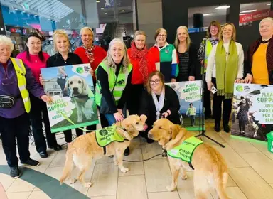 Group photo of Branch volunteers with the Askamore Singers, Honor Hefernan and Guide Dog Puncy and Milo