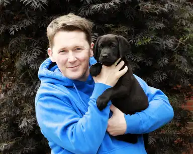 Shane Casey holding with Pup Casey  in his arms, looking straight to camera