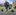 A young boy with a dog poses for a photo with life-sized character statues including Gru and two Minions from "Despicable Me" at an amusement park or carnival.