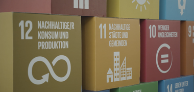 Die Ziele für nachhaltige Entwicklung der UN als bunte Kartons aufeinander gestapelt.
